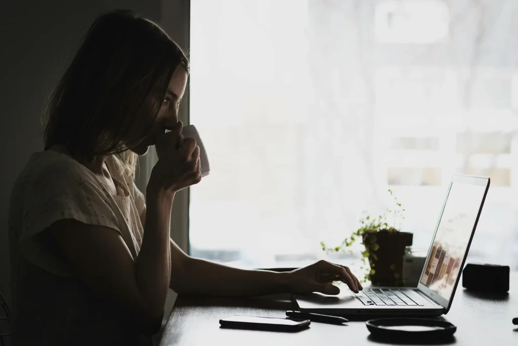 Γυναίκα που δουλεύει στον υπολογιστή και πίνει καφέ